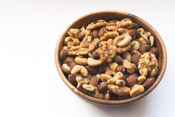 Mixed nuts in a bowl on a white top. Almonds, cashews, walnuts.