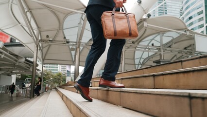 Close up of businessman leg walking up stairs surrounded by urban view. Back view of ambitious...