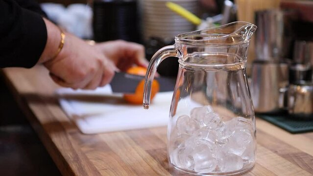 Bartender cutting up orange while making tropical lemonade in the pitcher