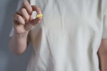 A woman's hand holding a vitamin capsule. Vitamins for women.