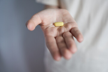 Yellow pill in the palm of a woman's hand. The concept is vitamins for health.