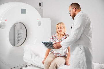 Medical computed tomography or MRI scanner. Doctor holding and explaining results of MRI. Woman...