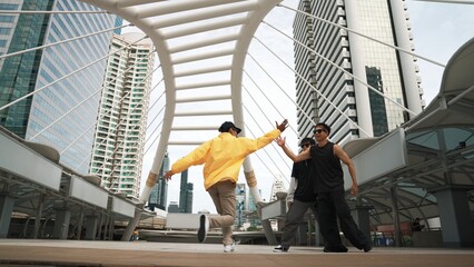 Group of professional street dancer cheer up while asian hipster perform freestyle footstep at city...