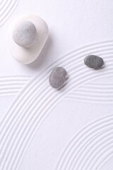 Fototapeta na wymiar Zen garden stones on white sand with pattern, flat lay. Space for text