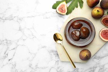 Jar of tasty sweet jam and fresh figs on white marble table, flat lay. Space for text