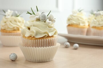 Tasty Easter cupcakes with vanilla cream on wooden table, closeup