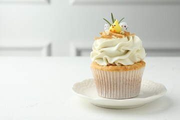Tasty Easter cupcake with vanilla cream on white table, space for text