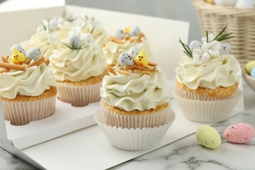 Tasty Easter cupcakes with vanilla cream on white marble table