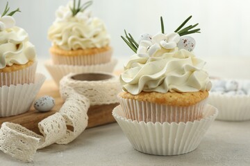 Obraz na płótnie Canvas Tasty Easter cupcakes with vanilla cream and ribbon on gray table