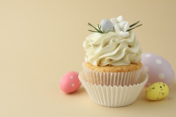 Tasty Easter cupcake with vanilla cream and candies on beige background, space for text