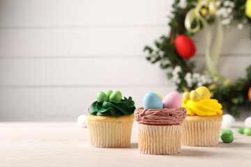 Tasty decorated Easter cupcakes on wooden table, closeup. Space for text