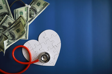 A stethoscope on money and a puzzle heart. Health insurance. Healthcare and medicine. How much is...