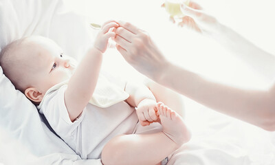 Maternity concept. A young mother feeds her little baby. First lure and breastfeeding. Family in white clothes.