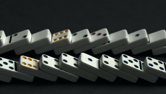 spaced line of white dominoes topples sequentially from left to right across a smooth