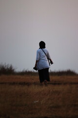 woman walking towards sunset on a field
