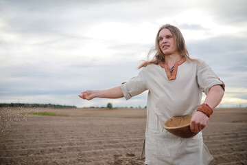 A young peasant sows the field with grain