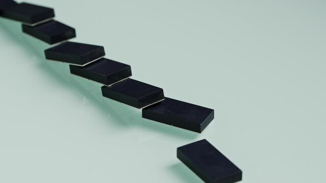 Watch as a series of dominos are arranged in a vertical line, with each piece balanced carefully on top of the next.