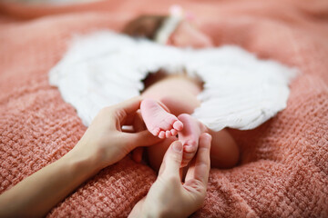 A newborn baby lies in her mother's arms. A beautiful baby of European appearance is sleeping.