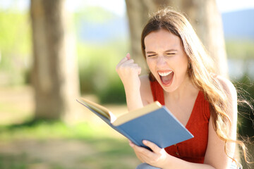 Excited woman reading a paper book in a park