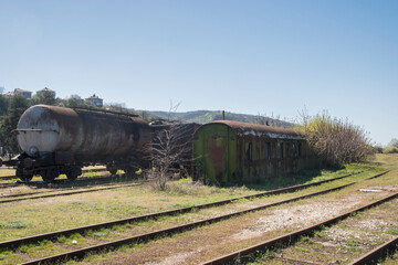 Fototapeta na wymiar Old rusty abandoned railway oil tankers in the middle of a field on sunny day