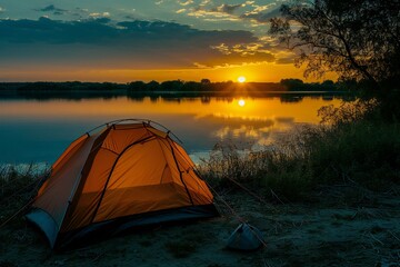 Camping tent on the shore of a lake at sunset in summer