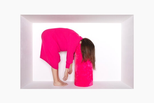 Teenage girl bending over pink bolster in alcove