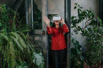 Smiling businesswoman gesturing with virtual reality simulator in office doorway
