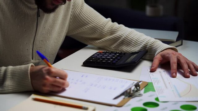 Man Calculating Budget With Calculator and Paperwork at Home Office Desk