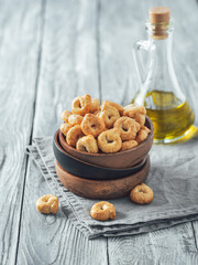 Traditional italian snack taralli or tarallini in wooden bowl over old gray wooden table. Rustic shot of taralli appetizer with copy space. Vertical.