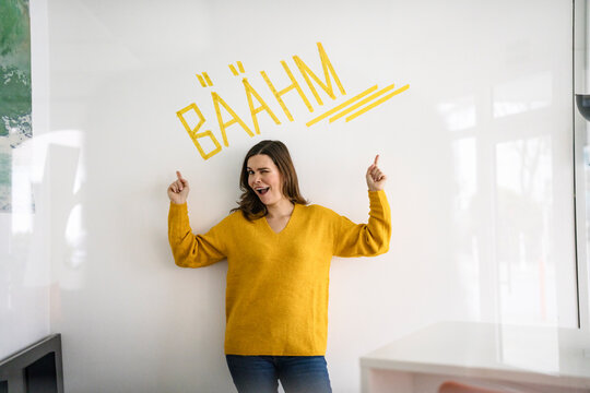 Creative businesswoman pointing at text in front of white wall with text in office