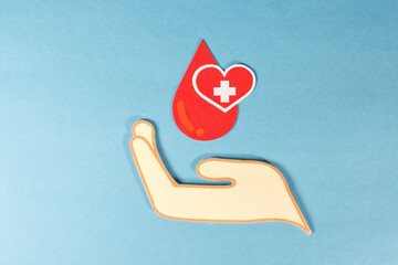 A hand holding red drops of blood, blood donation concept.