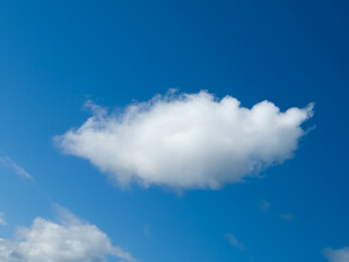 Single white fluffy cumulus cloud in the blue summer sky