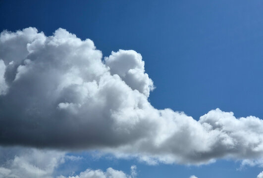White fluffy cumulus clouds background. Summer clouds in the blue sky