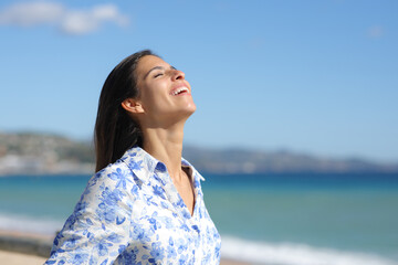 Happy woman laughing and breathing fresh air on the beach