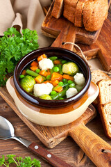 Bowl of delicious vegetables soup on wooden table