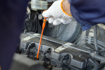 Closeup mechanic hand with protective glove checking the oil level of a car. Routine car...
