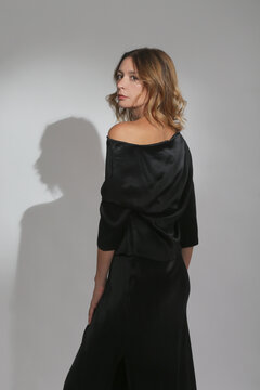 Serie of studio photos of female model wearing black maxi silk dress
