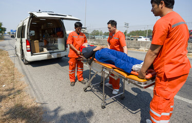 Group of paramedic or emergency medical technician (EMT) in orange uniform helping neck and head...