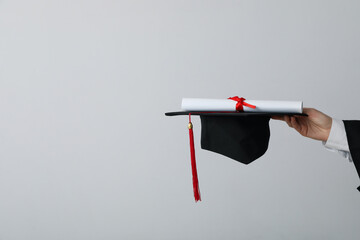 Diploma and hat of a university graduate, on a gray background.