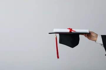 Poster Diploma and hat of a university graduate, on a gray background. © Atlas
