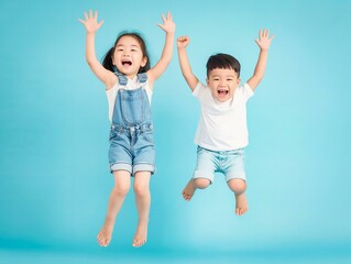 Two children are jumping in the air, one is wearing a blue outfit and the other is wearing a white outfit. Scene is joyful and playful