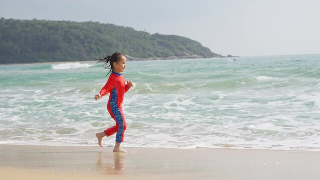 Happy little asian girl running on the beach in the morning at Wanning Shimei Bay of Hainan China