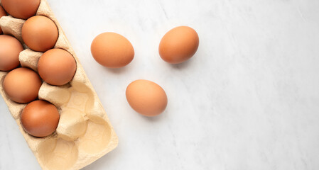Egg in pack on white marble table,
Pile of brown chicken eggs top view - 773821967