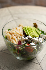 Salad with quinoa, avocado and feta cheese in a glass bowl