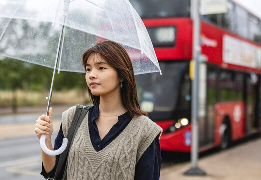 close up portrait of young asian woman with her umbrella at the bus station