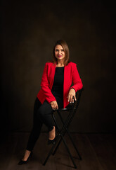 Fototapeta na wymiar A woman in a red jacket sits on a black chair