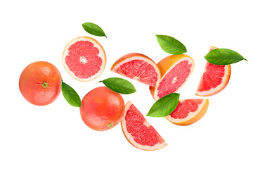 Fresh ripe grapefruits and green leaves falling on white background