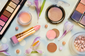 Different makeup products and beautiful crocus flowers on light blue background with space for...