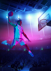 Slam dunk. Competitive young man, basketball player throwing ball into basketball hoop in a jump on gradient stadium background with spotlights. Concept of sport, action, game, competition, tournament