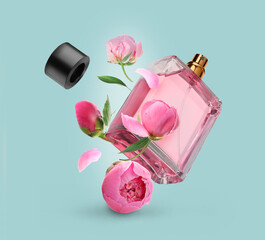 Bottle of perfume and peonies in air on light blue background. Flower fragrance